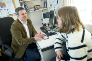 Image of a GP talking to a patient in a consulting room.