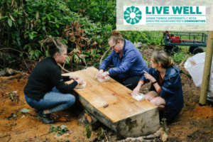 Image of people outside doing some therapuetic gardening. GM live Well logo top right of image