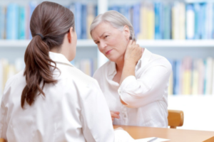 Image of a person having a consultation. They are holding their neck in pain