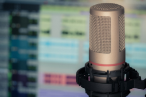 Image of a microphone. Studio equipment in the background which is slightly blurred