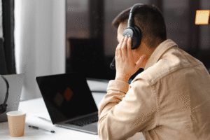 Image of a person sat in front of a laptop listening through headphones