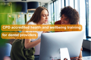 Image of a person sat at a desk looking at a laptop. Another person is leaning over them and they are talking. Text over the image reads: CPD accredited health and wellbeing training for dental providers